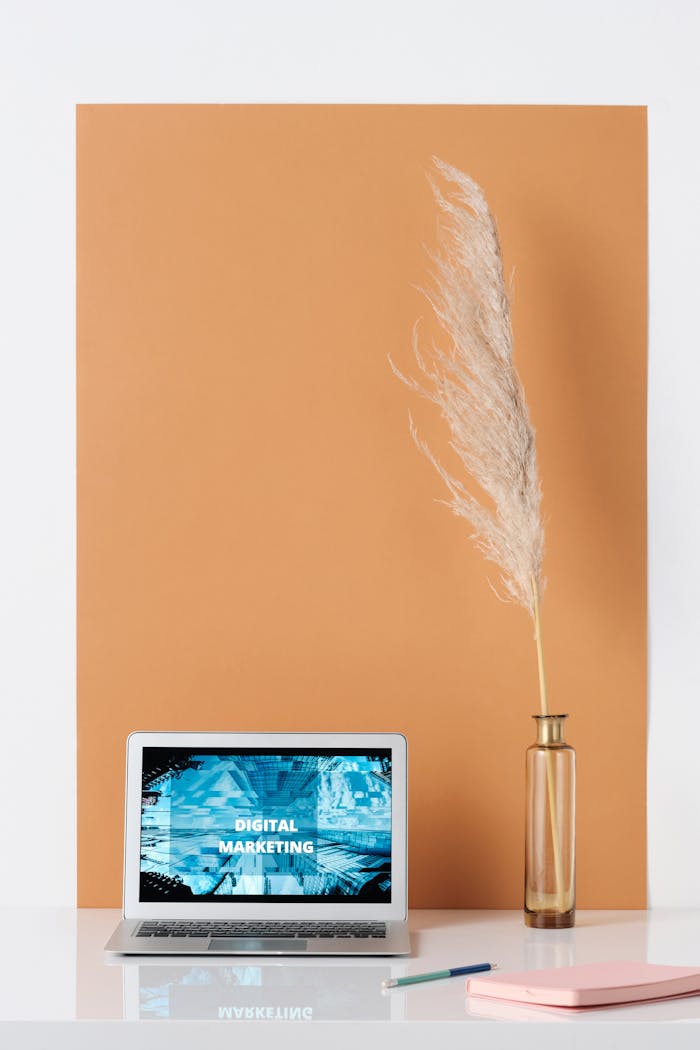 Stylish minimalist workspace with laptop showing digital marketing, vase with pampas grass, and copy space.